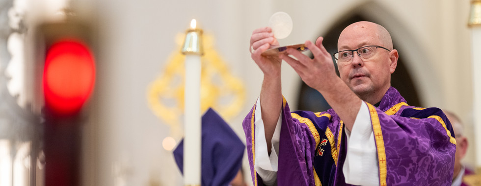 Obispo eleva la hostia consagrada durante la consagración en la Eucaristía.