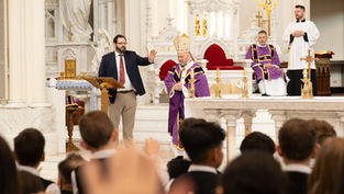 Un obispo en púrpura oficia en un altar dorado dentro de una iglesia, rodeado de asistentes. Ambiente solemne y reverente.