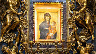 Ornate gold religious altar with angels around a blue-framed Madonna and Child icon, Greek letters visible, solemn and reverent
