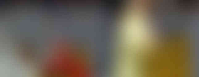 Bishop in white and gold robes speaks at a podium during a religious gathering. A cardinal in red sits nearby. Attendees in white fill the background.