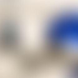 European Union flag with yellow stars waving in the wind in front of a historic stone building with arched windows.