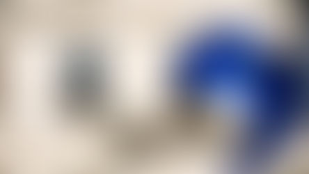 European Union flag with yellow stars waving in the wind in front of a historic stone building with arched windows.