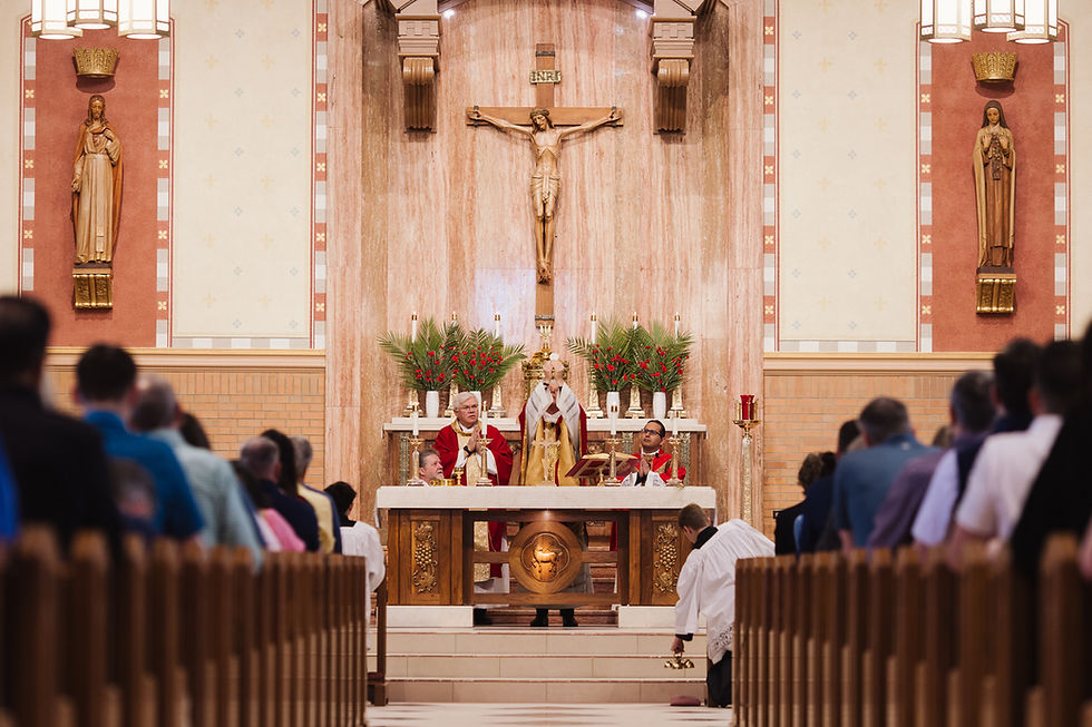 Catholic mass in a church: priests at the altar beneath a crucifix, with congregation kneeling in the pews.