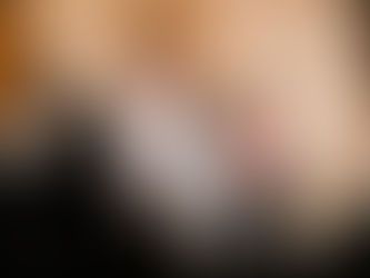 Priest in ornate robe blesses congregation inside a church. Attendees in dark clothing. Background shows altar and gold cross.