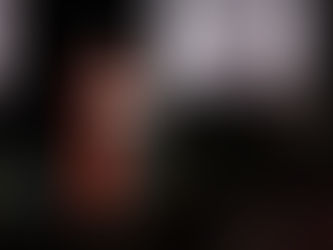 A man in red robes speaks at a podium on stage, flanked by banners and people. A sign reads "MAS DE LO QUE CREES.ORG" in the background.