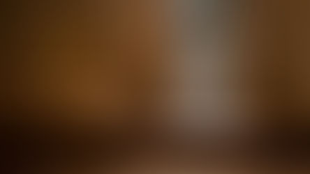 Man seen through a confessional screen in a wooden booth. The setting is dimly lit, conveying a solemn, contemplative mood.