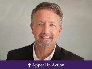 Hombre sonriente con barba, fondo gris claro. Lleva traje oscuro y camisa blanca. Texto: "Appeal in Action" en fondo morado.