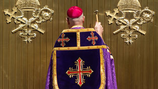 Sacerdote en vestimenta púrpura toca una puerta dorada con martillo, decorada con símbolos religiosos. Ambiente solemne y ceremonial.