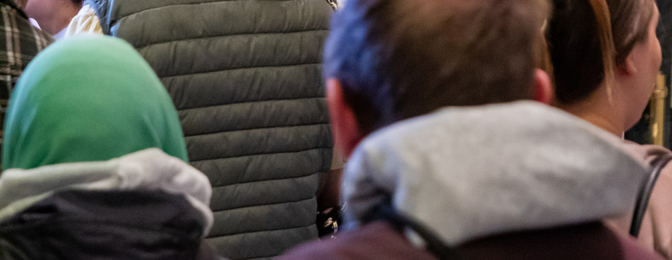 The bishop greets parishioners after Mass in a crowded church vestibule.