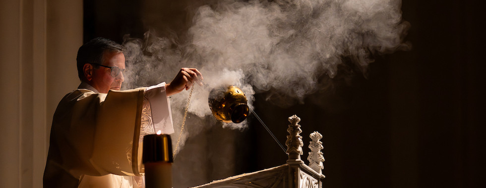 A deacon swings a thurible, releasing incense smoke during the liturgy.