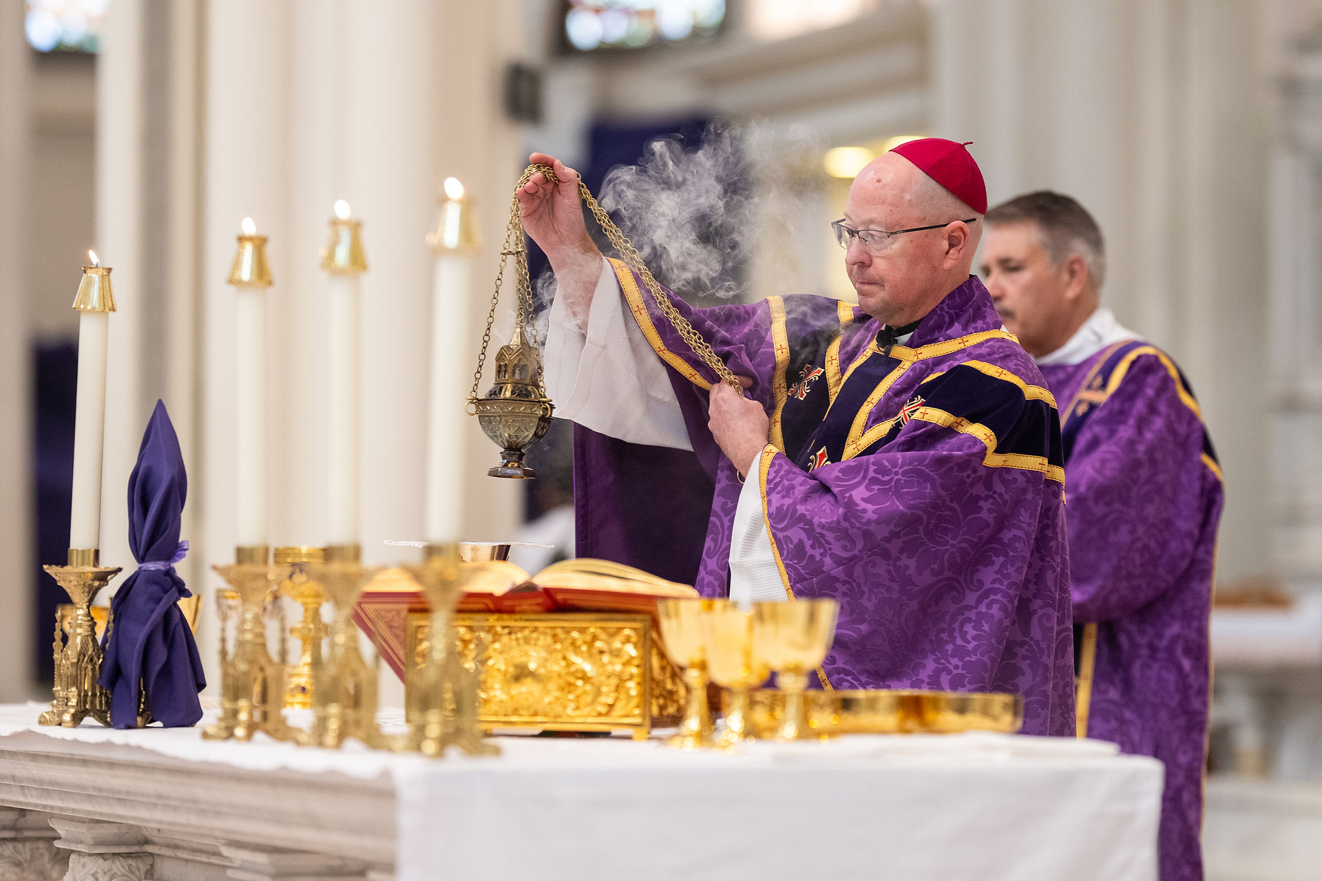 Obispo inciensa el altar con un incensario del que se eleva humo durante la Misa.