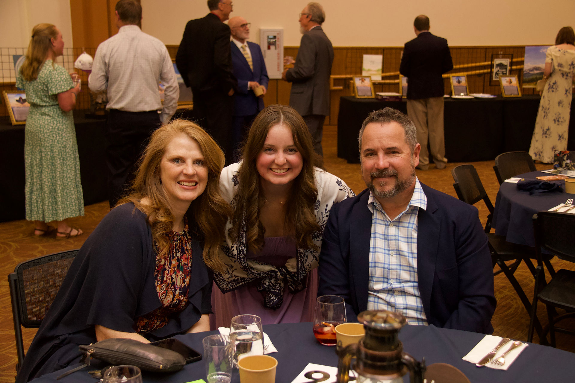 Family smiles for a photo while seated at a banquet table during a Catholic fundraising gala.