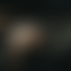 Hands typing on a laptop keyboard in dim light. Shadows and a plaid pattern in the lower left create a focused, moody atmosphere.