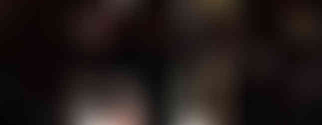 A priest kneels in prayer before the Eucharist on an altar, surrounded by a crowd holding lit candles in a dark setting.