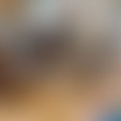 Group of people smiling and chatting around a table with drinks and a vase of flowers in a cozy café setting.