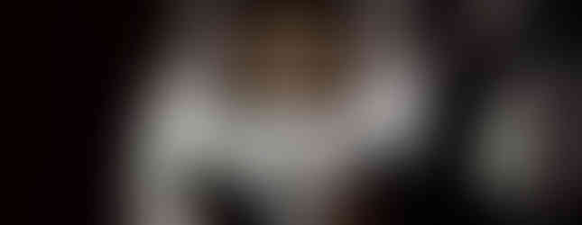 Silhouetted worshippers sit and pray quietly in pews inside a dimly lit church.