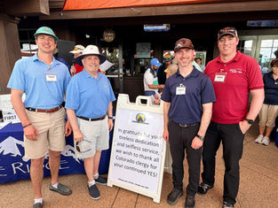 Four smiling men in golf attire pose outside a booth with a Catholic Radio Network thank-you sign at a scouting event.