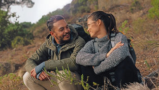 Una pareja sentada durante una caminata en las montañas.