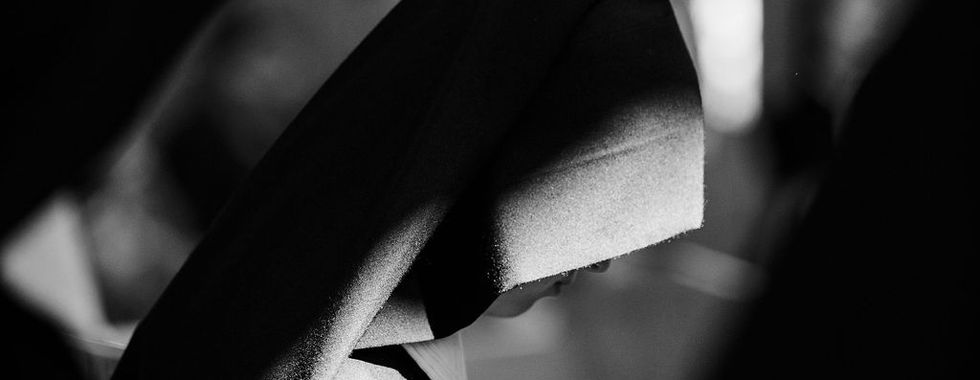 A black-and-white portrait captures a religious sister in silent prayer during the vows ceremony, illuminated by a beam of light.