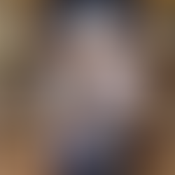 A family of four stands in a church. Parents in gray, daughters in plaid uniforms. The father holds a religious item. Blue altar backdrop.