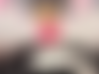 Elderly woman in pink stands smiling behind a birthday cake with floral decoration and "Happy 101st Birthday Peggy!" banner and balloons behind.