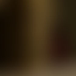 Golden tabernacle with engraved cross beside a glowing red candle in a dimly lit setting, creating a serene and reverent atmosphere.