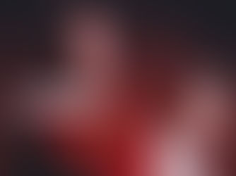 Sacerdote con túnica roja y blanca sostiene una hostia iluminada sobre fondo rojo; escena solemne y contemplativa.
