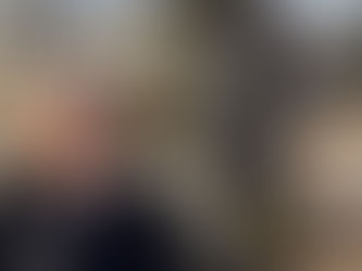 Woman in black shirt smiling outdoors near a religious statue with flowers. Sunny day, natural setting, and peaceful mood.