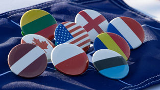 Flag pins arranged on a blue fabric backdrop. Bright colors feature flags of several countries, creating a sense of unity and diversity.