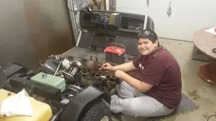 Teen fixing golf cart engine, smiling, in garage. Red toolkit on seat, assorted wires visible. Warm lighting, relaxed mood.