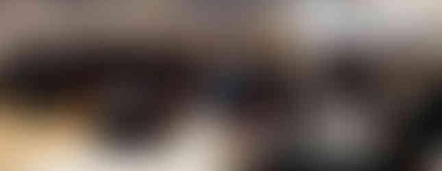 A large group of people stands and applauds at a conference in a banquet hall with black tablecloths and red chairs, creating an energetic atmosphere.