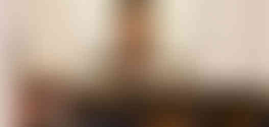 People praying in a church before a statue of Our Lady of Guadalupe. Lit candles and flowers adorn the altar, creating a serene atmosphere.