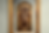 Tall framed medieval icon of a haloed saint holding a scroll with Latin text, surrounded by small biblical scenes in a museum gallery