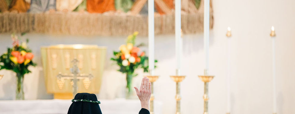 A newly professed sister kneels in prayer before the altar during Mass.