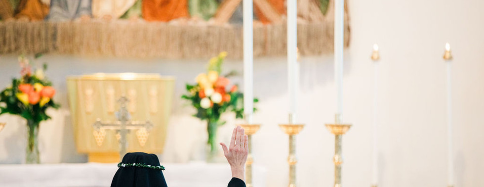 A newly professed sister kneels in prayer before the altar during Mass.