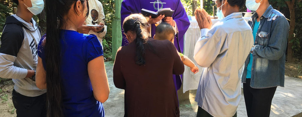 El padre Paul bautiza a un bebé recién nacido durante una visita pastoral misionera a una aldea.