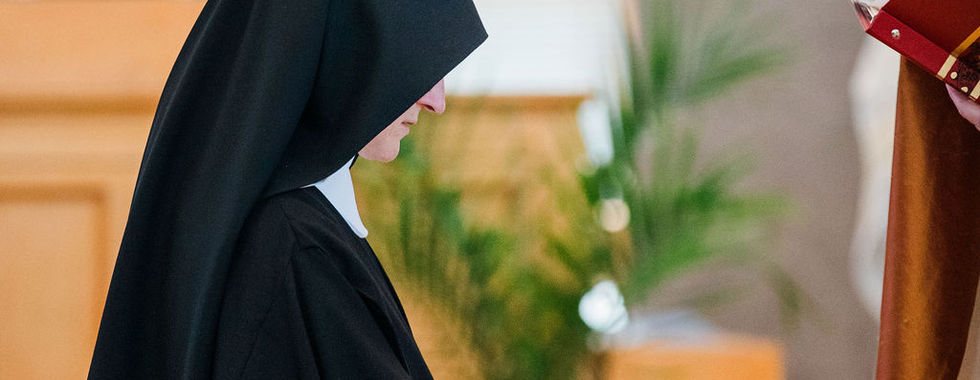 An archbishop extends a blessing over a newly professed sister during the vows ceremony.