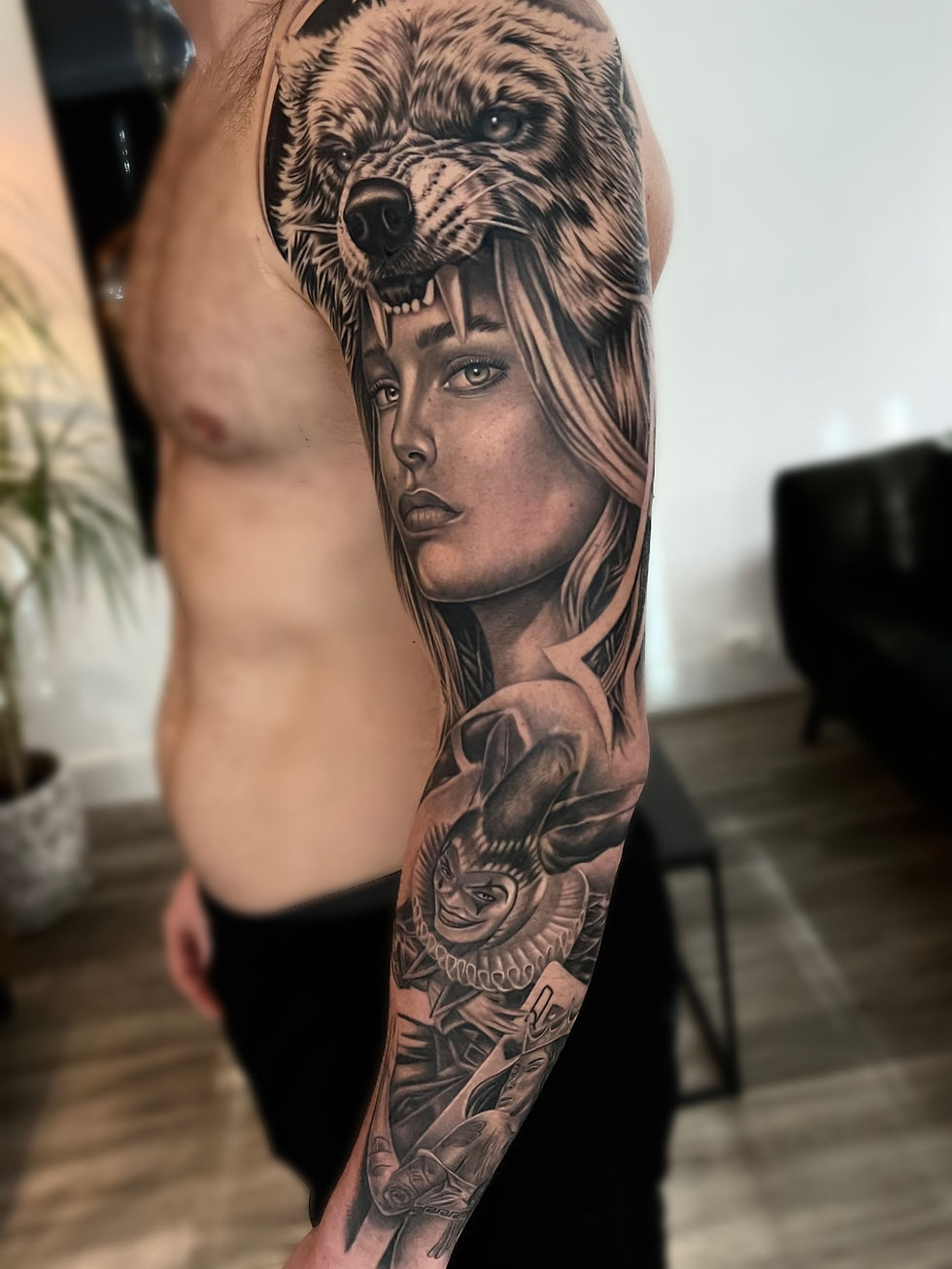 Sleeve tattoo met een wolf en een vrouwengezicht boven, en een speelse joker onder.