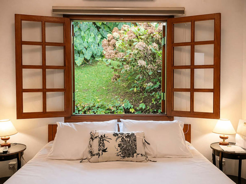 Suíte Essencial da Tília Pousada de Charme em Campos do Jordão com cama aconchegante e decoração acolhedora com vista para a natureza