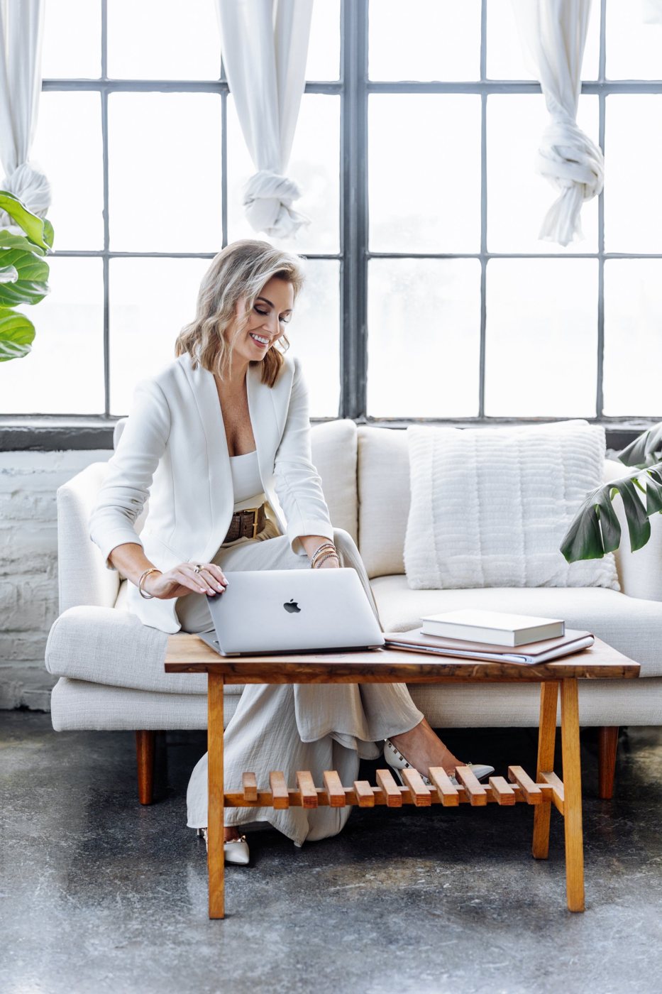 Jillian in a white suit working on her laptop