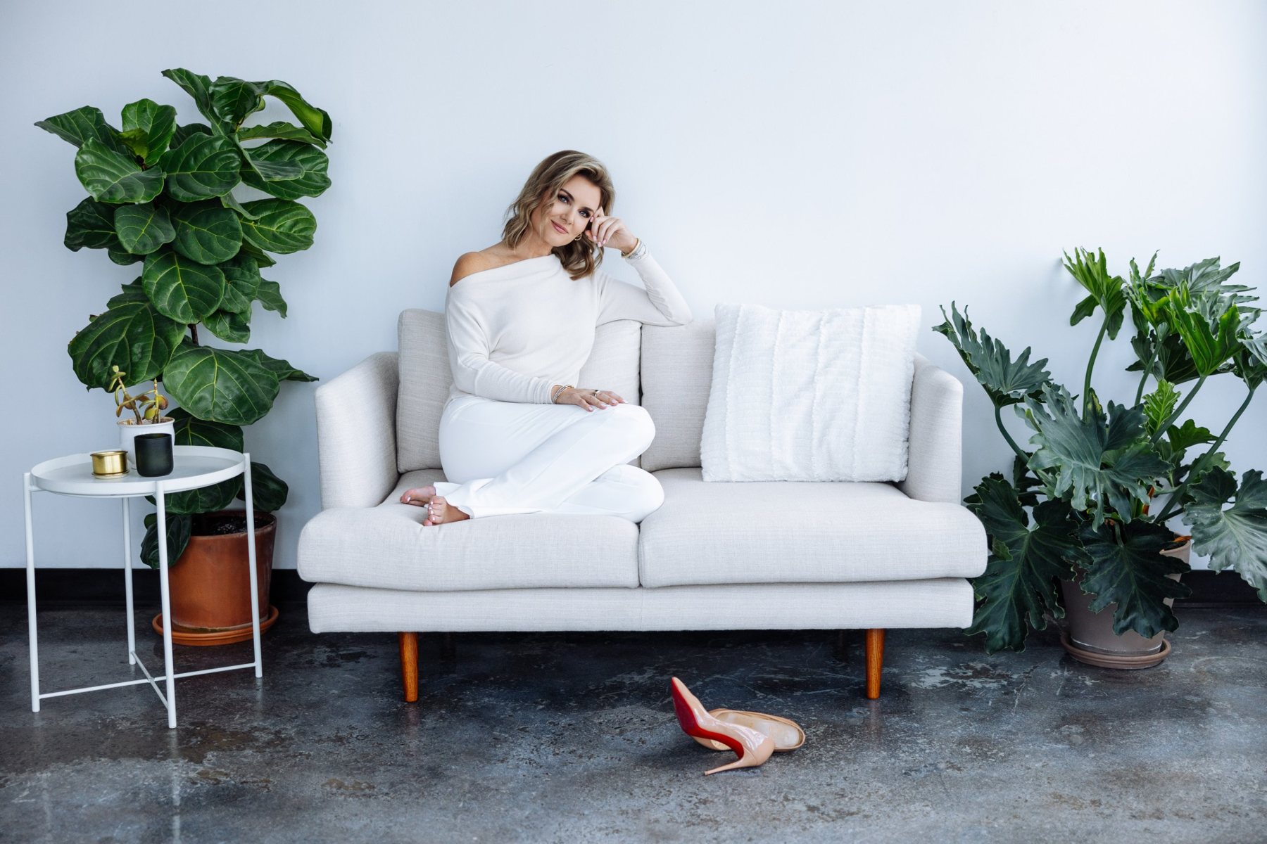 Jillian relaxing barefoot on a white couch, her heels on the floor