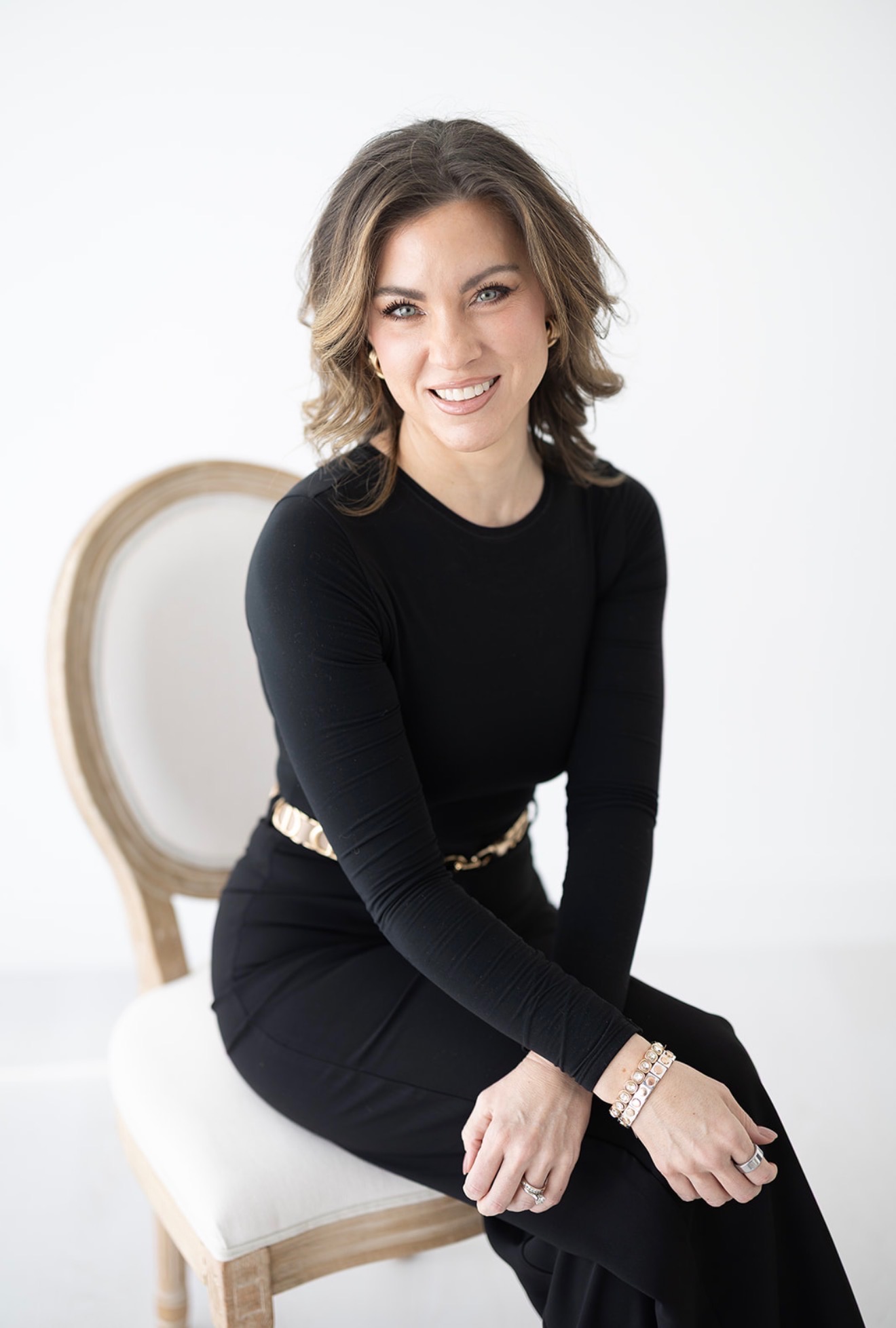 Erin Stringer smiling, seated on a cream chair in a black top