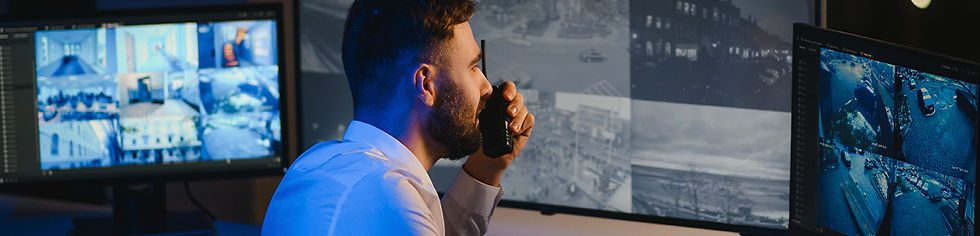 Image of security man looking over monitors of CCTV footage