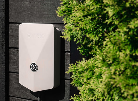 Evnex charger instaled on external fence with bush in foreground