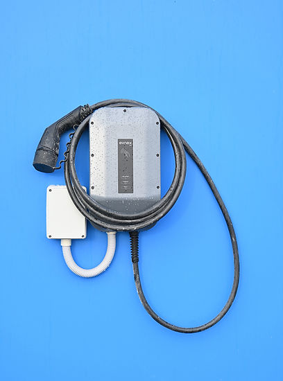 External evnex charger install on blue wall covered in rain