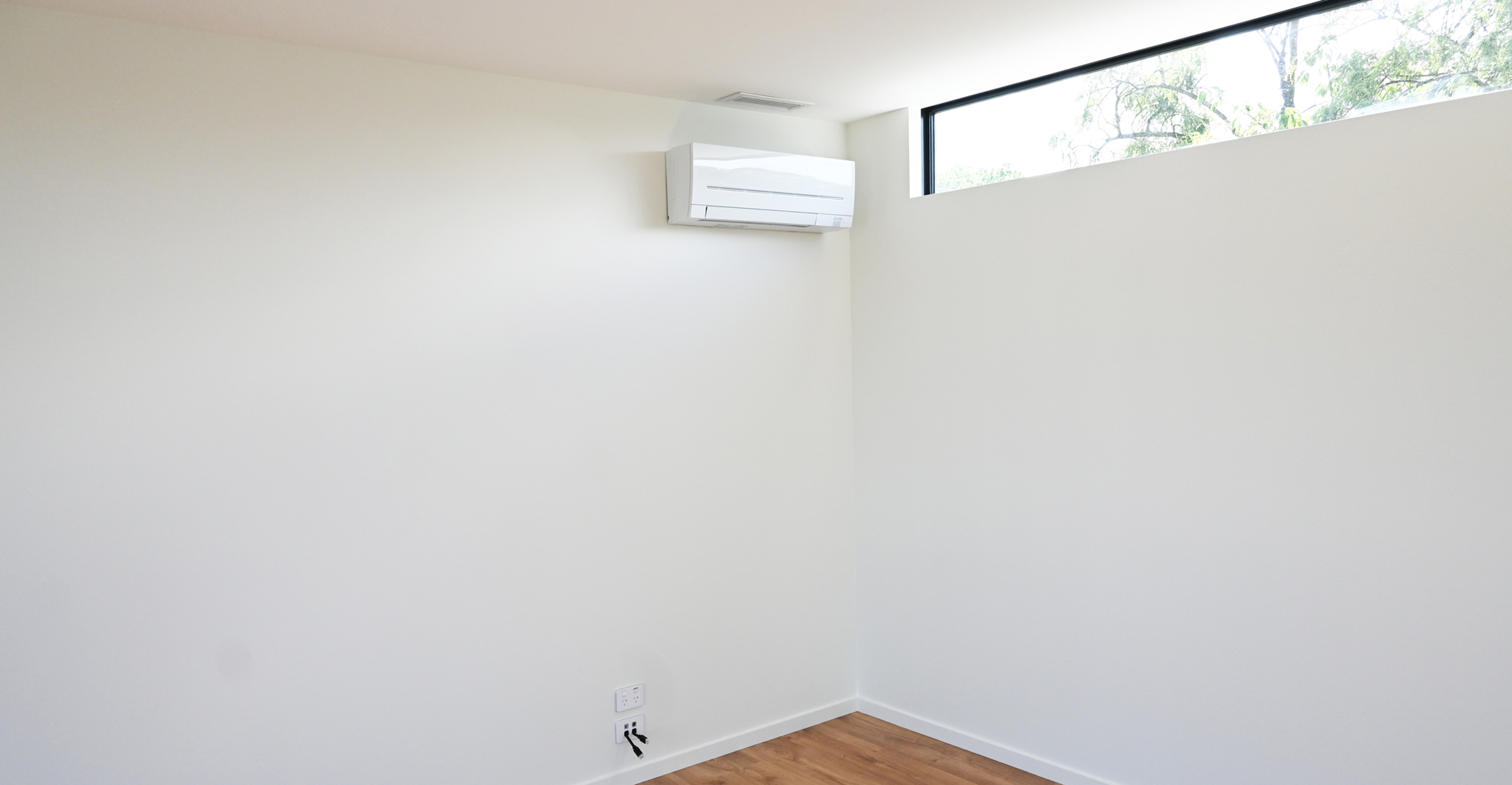 Mitsubishi Electric heat pump installed in bedroom with wooden floors and lossnay ventilation vent above in roof