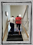 Home physio visit. Physiotherapist helping a lady with crutches go up the stairs.
