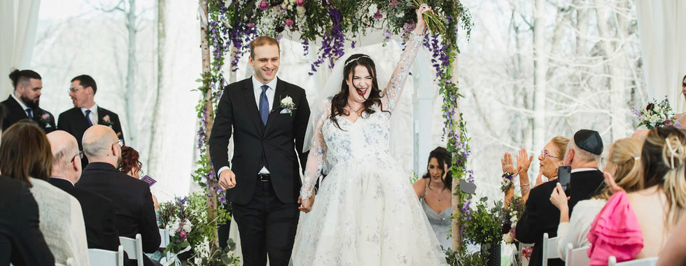 Bride and groom happily cheers under their wedding chuppah post-ceremony.