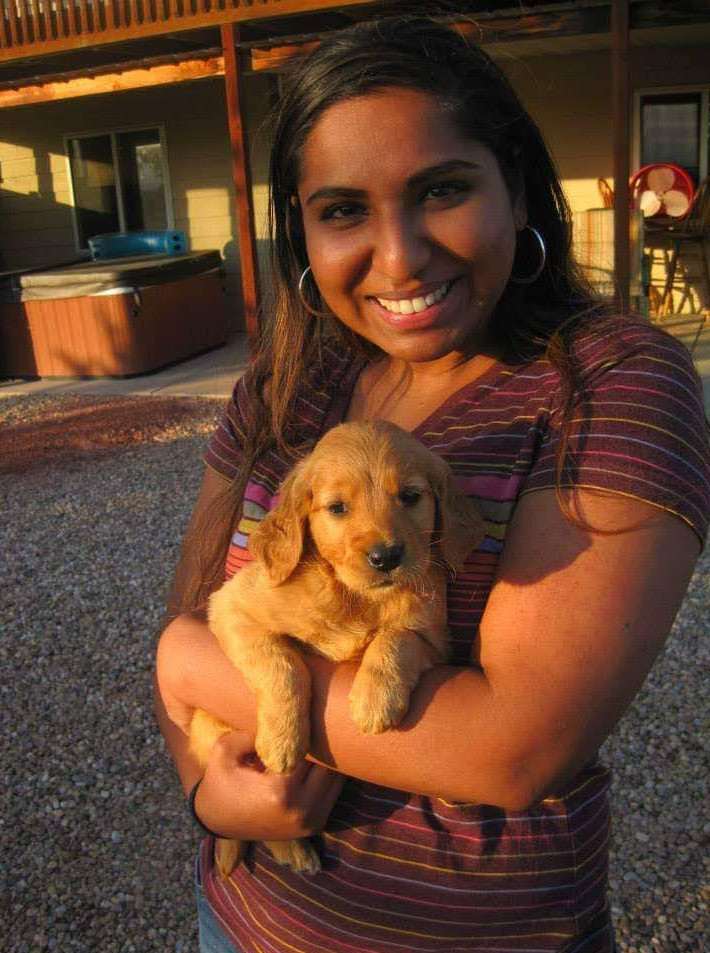 portrait of a smiling woman holding a small puppy outdoors at sunset, warm colors, portrait orientation
