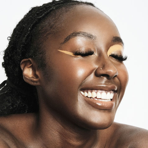 Black model smiling with orange eye makeup 